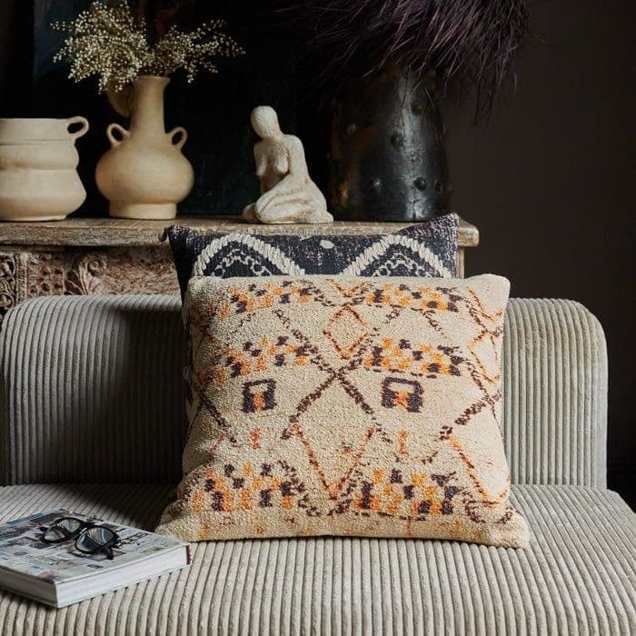 The House look cushion on a greay sofa with a book