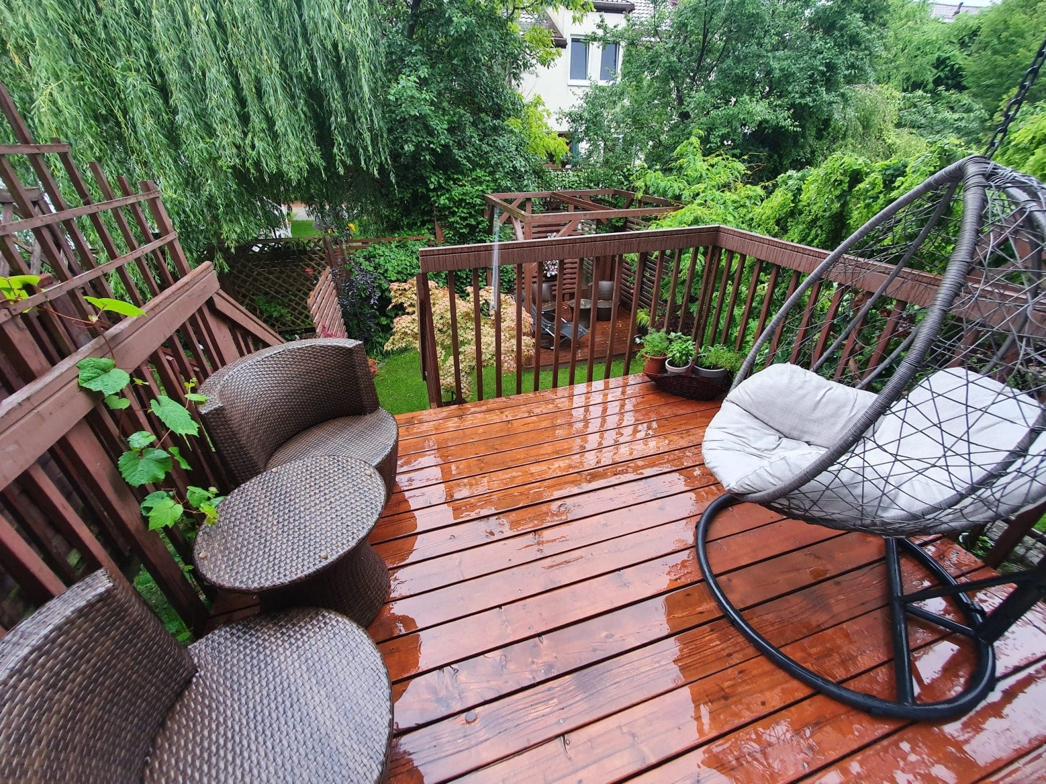 Outdoor furniture wooden chairs and an egg chair on wooden patio