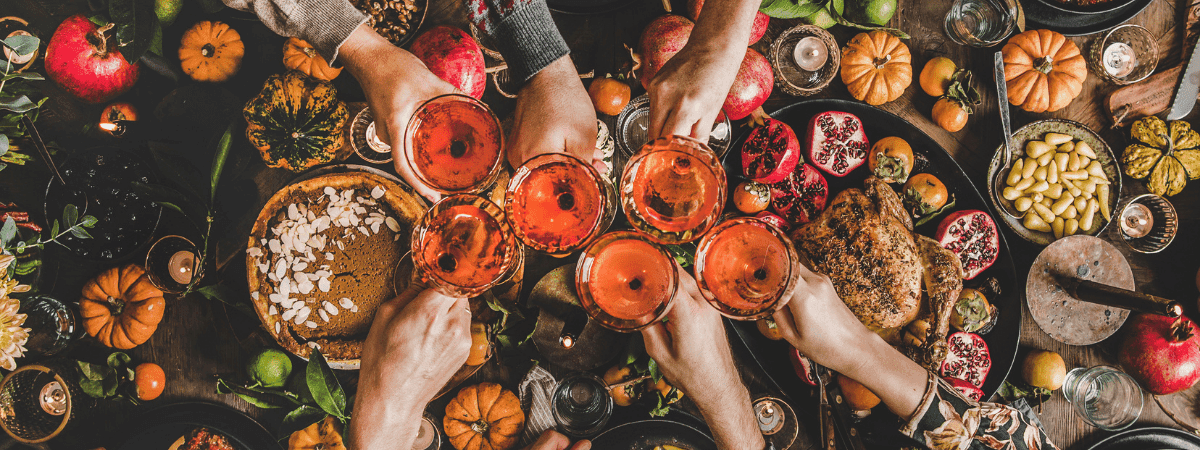 several people clinking drinks and celebrating over a table of a banquet of food